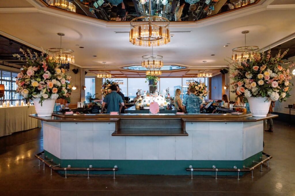 Bar area at L.A. Jackson rooftop bar in Nashville, Tennessee, decorated with floral arrangements and city views.