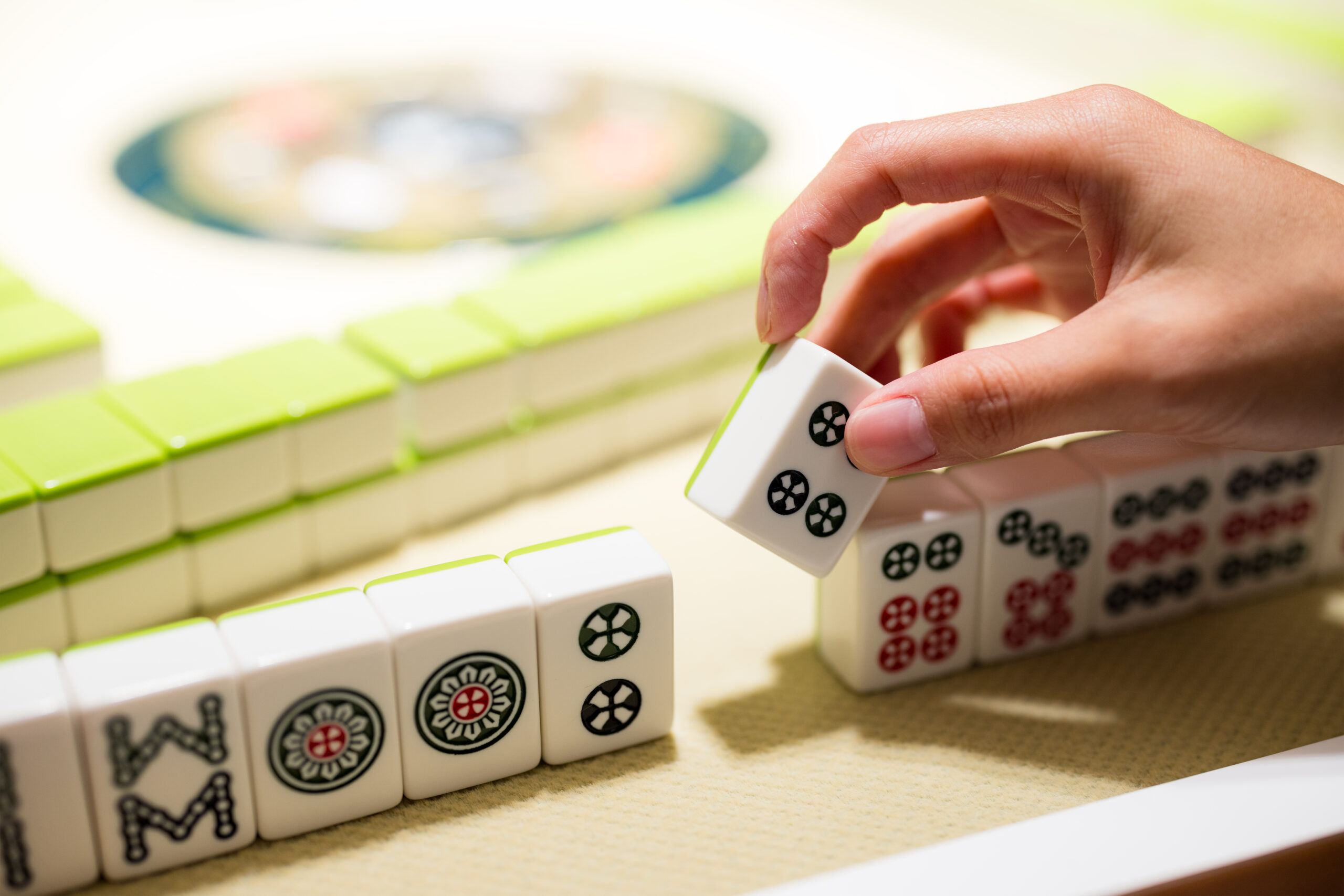 Local Mahjong meetup groups in Franklin, Brentwood, Spring Hill and Williamson County, TN, hand placing a green and white Mahjong tile during a local meetup game.