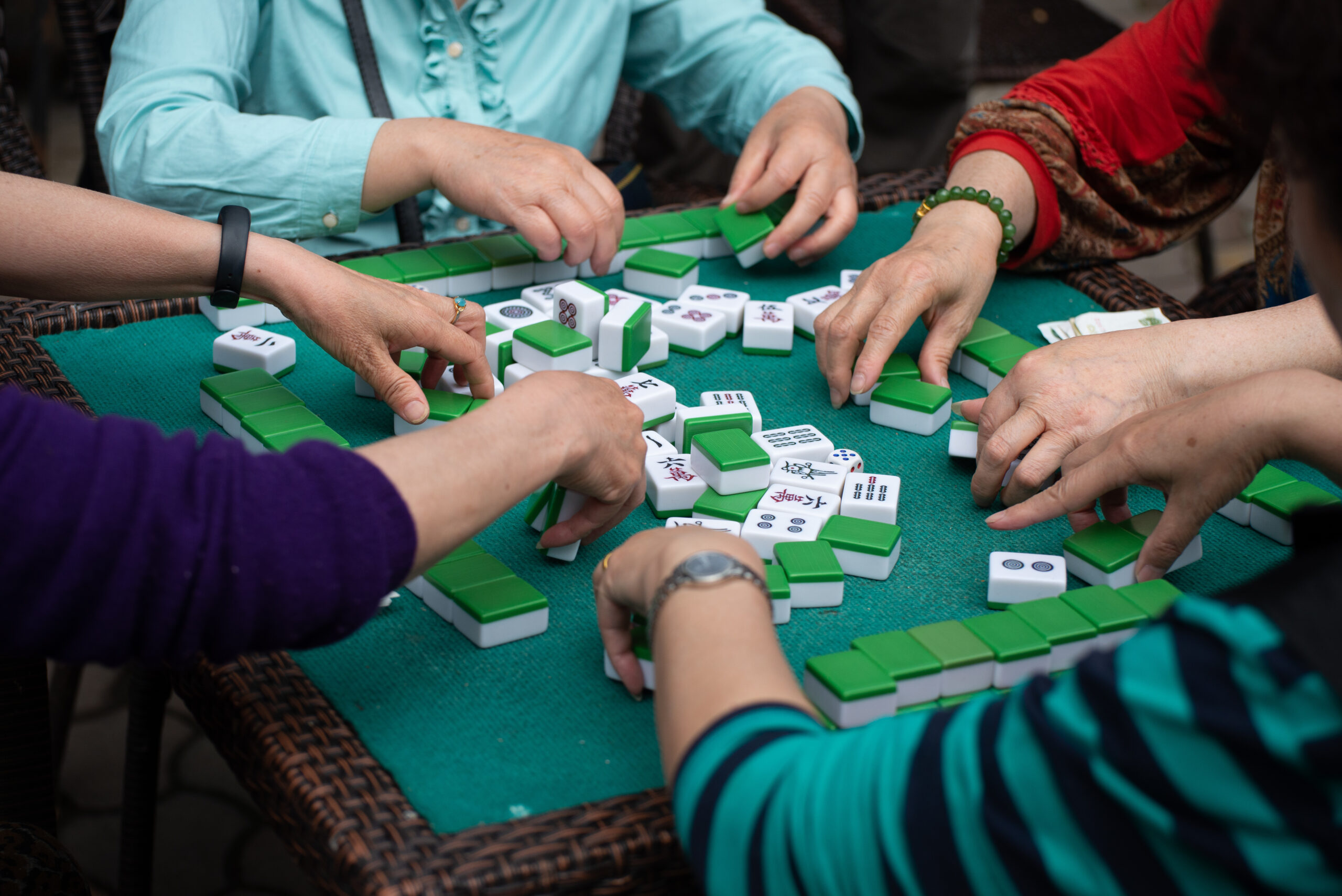 Mahjong programs for Adults 55 and older in Franklin, Brentwood, Spring Hill, Fairview and Williamson County, TN, adults playing Mahjong with green and white tiles at a community game table. 