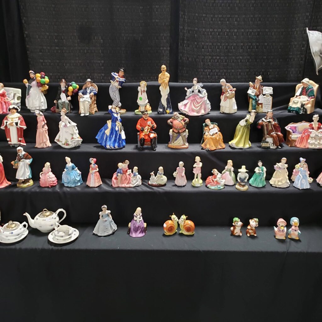 Display of collectible figurines, porcelain pieces, and vintage items at the Murfreesboro Antiques Show in Tennessee.
