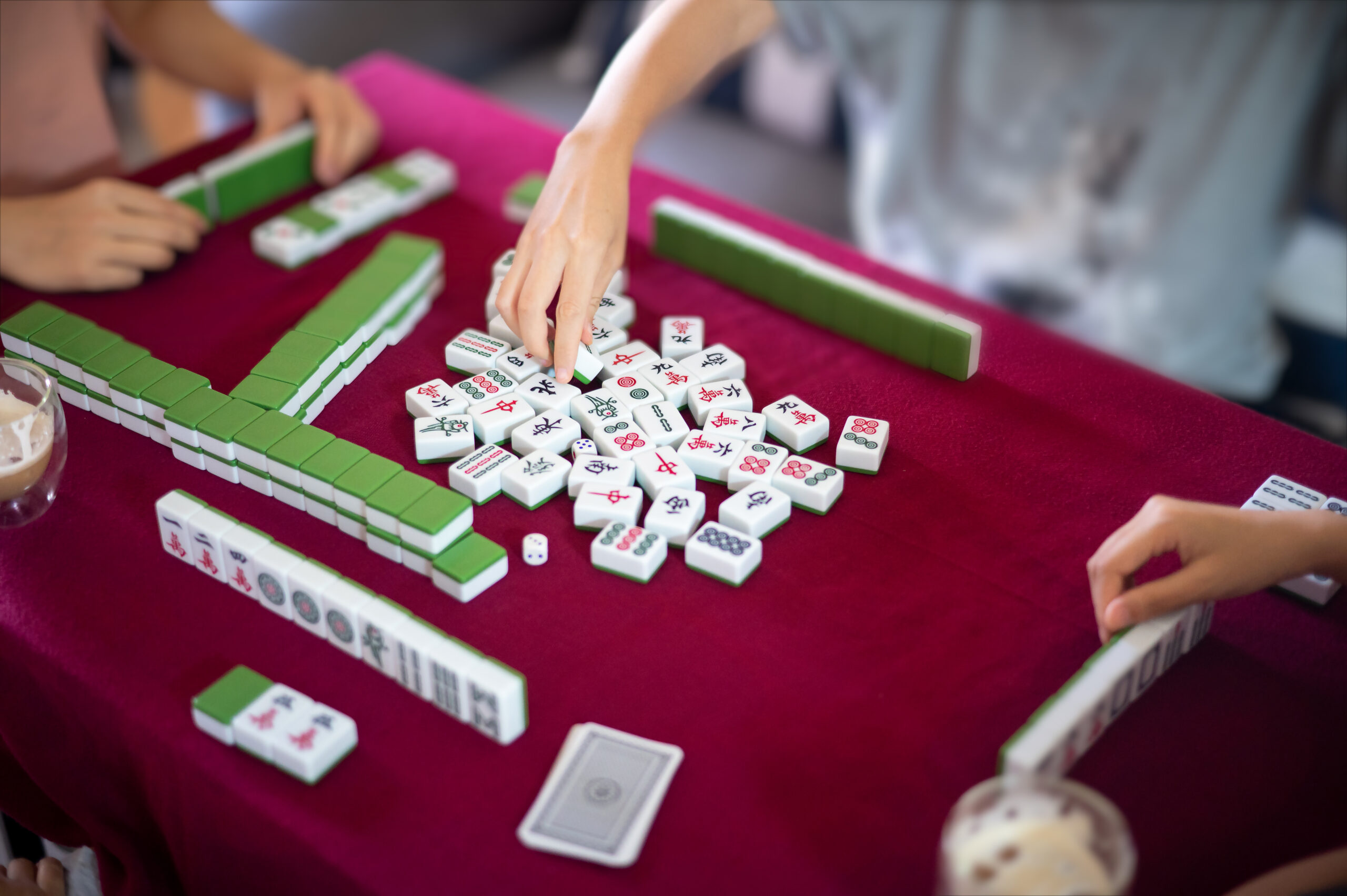 An open-play Mahjong event in Franklin where players arranging green and white Mahjong tiles during an open play game.