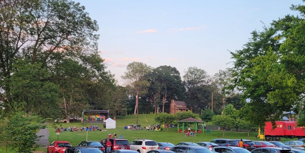 Visitors gathered on the lawn at Red Caboose Park in Bellevue, Nashville, with the park’s red train caboose visible nearby.