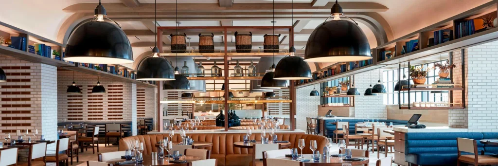 Interior of Stompin’ Grounds restaurant at JW Marriott Nashville with dining tables, booth seating, and an open kitchen.