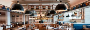 Interior of Stompin’ Grounds restaurant at JW Marriott Nashville with dining tables, booth seating, and an open kitchen.