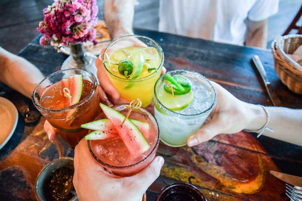 Franklin and Nashville, TN bars, friends toasting and saying cheers while holding tropical blended fruit margaritas, including watermelon and passionfruit drinks.