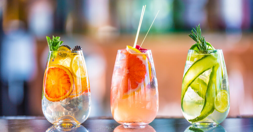 Three colorful gin tonic cocktails in glasses on bar counter in Nashville, TN.
