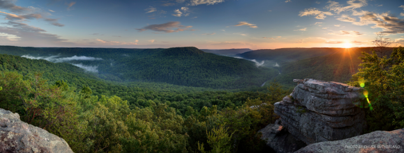 Forested Tennessee landscape at sunset with rocky overlooks, rolling hills, and mist-filled valleys.