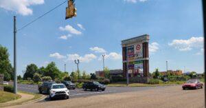 Entrance sign for The Crossings of Spring Hill shopping center in Spring Hill, Tennessee, with surrounding retail stores and traffic.