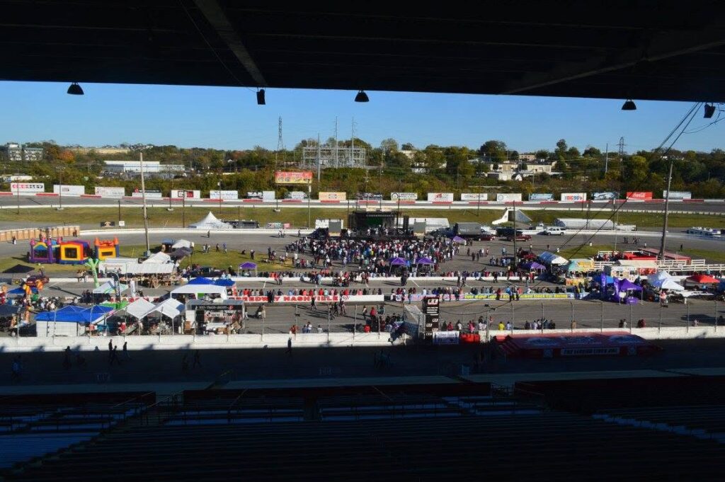 The Fairgrounds Nashville event complex with crowds, vendor tents, and an outdoor stage near the Nashville Fairgrounds Speedway.