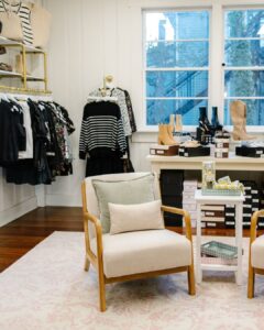Interior of The Statement Society women’s boutique with clothing, shoes, accessories, and seating.