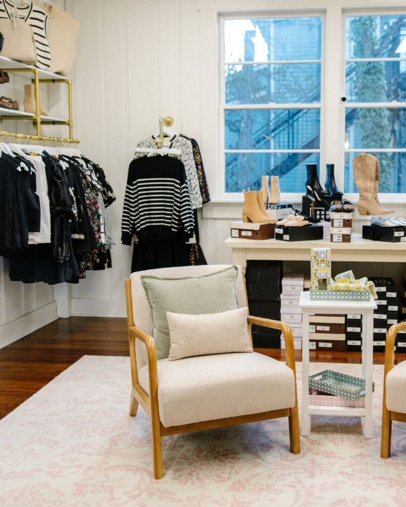 Interior of The Statement Society women’s boutique with clothing, shoes, accessories, and seating.
