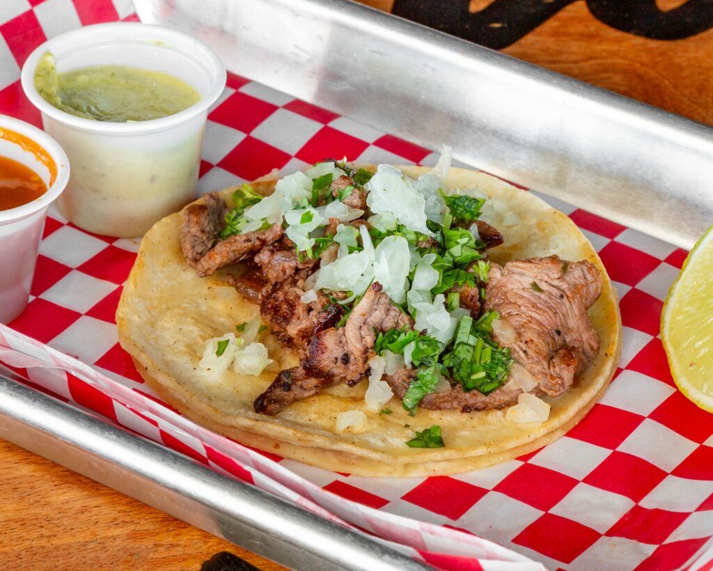 Steak taco from The Taco Shop in Franklin, Tennessee, topped with onion and cilantro and served with salsa and lime.