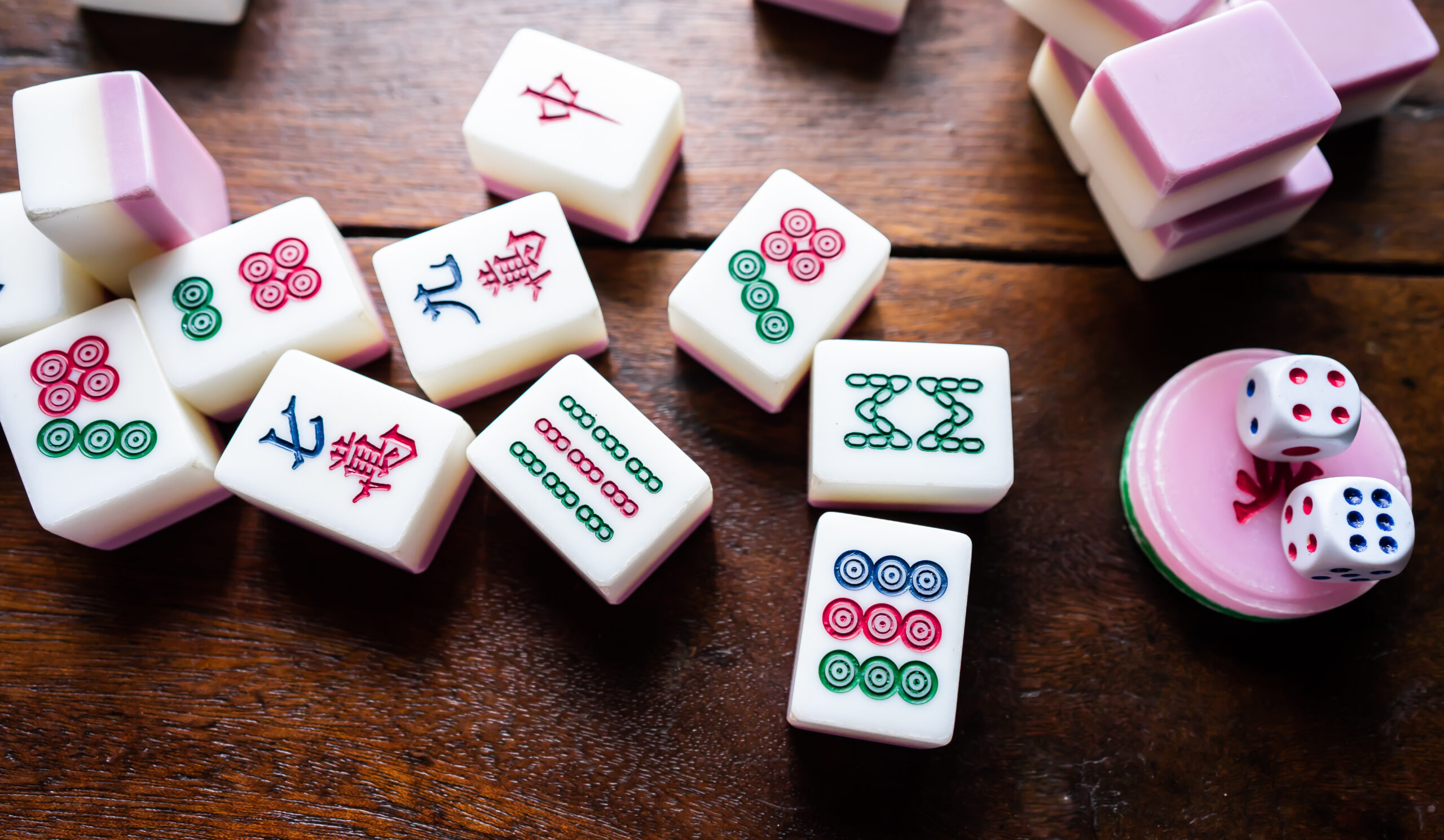 A game of Mahjong in Franklin, Tennessee, with colorful Mahjong tiles and dice arranged on a wooden table.