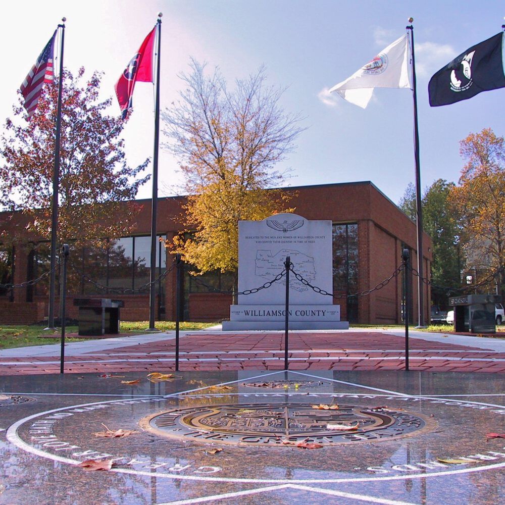 Williamson County Veterans Park in Franklin, Tennessee, with military flags, memorial displays, and engraved brickwork.