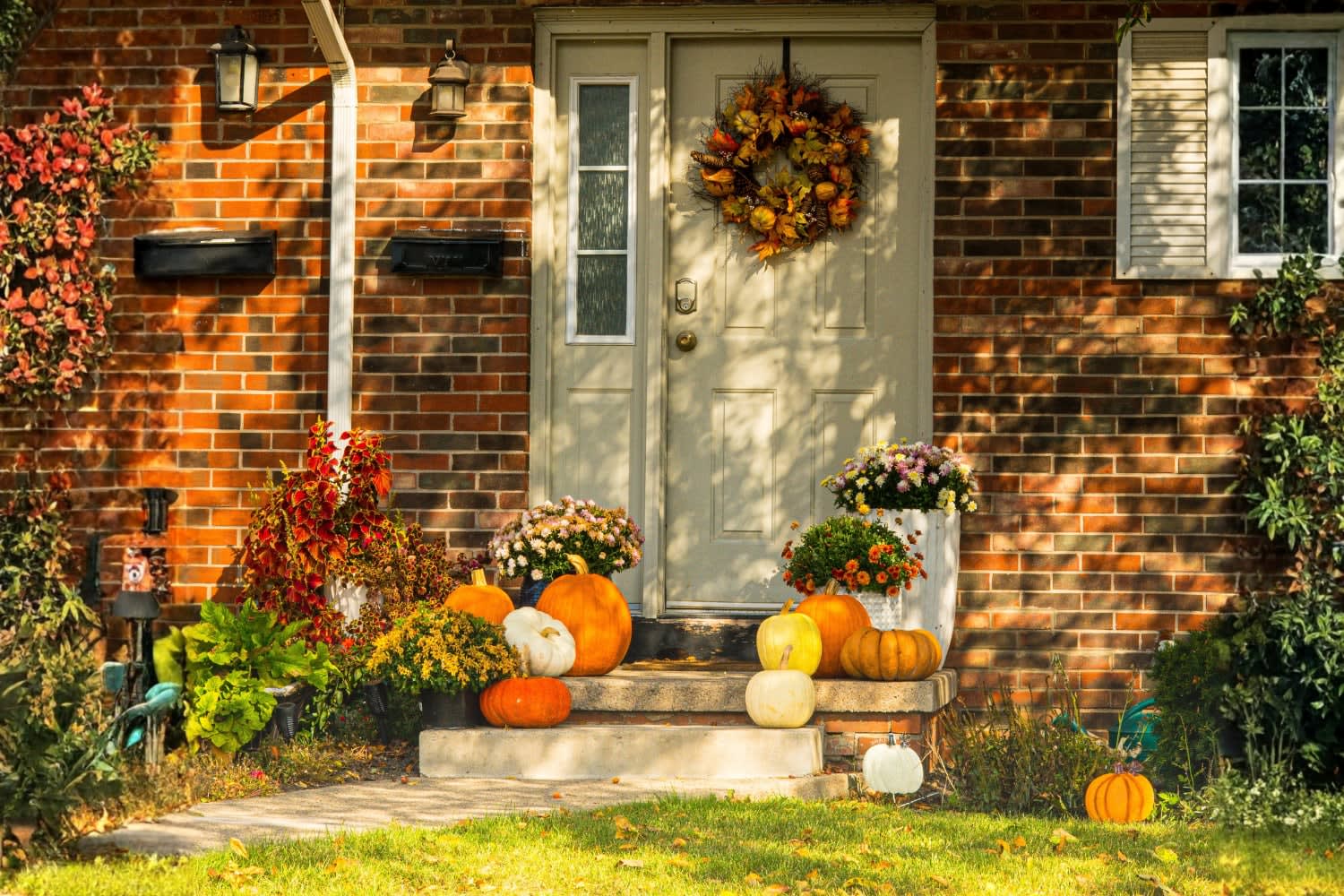 Fall porch decorated with pumpkins, mums, seasonal plants, and a wreath by Gourdgeous Porch Designs in Franklin, TN