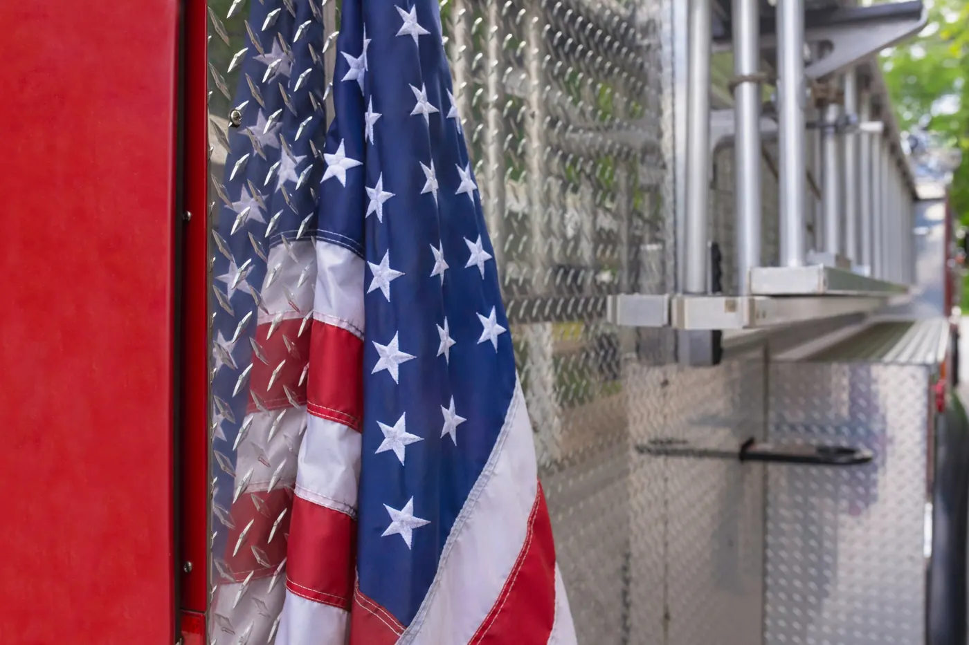 American flag hanging alongside the red and silver exterior of a fire truck.