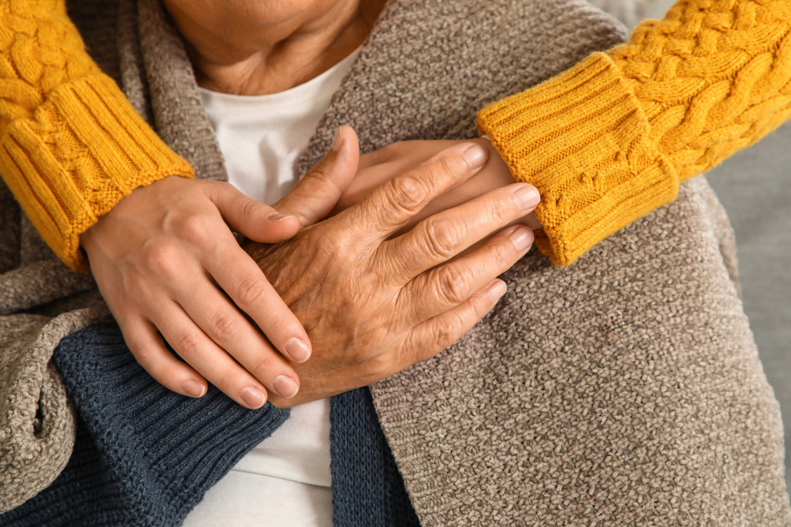 Caregiver holding an older adult's hands, illustrating the support and protection offered through the Home Safe Franklin program.