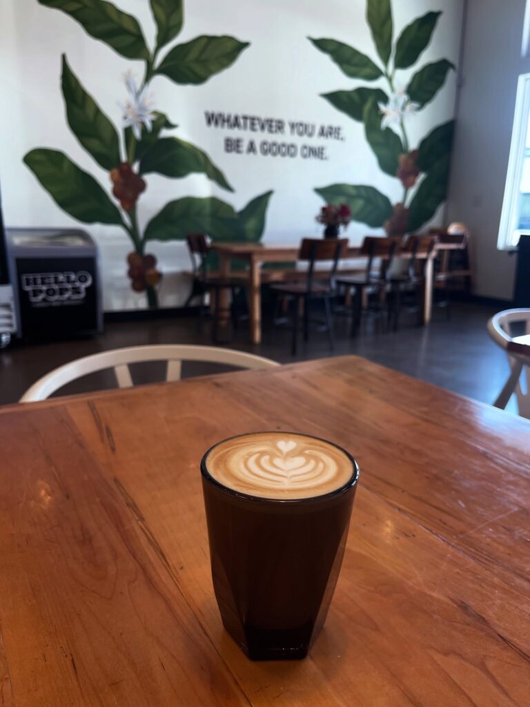 Latte with leaf-shaped foam art on a wooden table inside Honest Coffee Roasters at Berry Farms in Franklin, Tennessee.