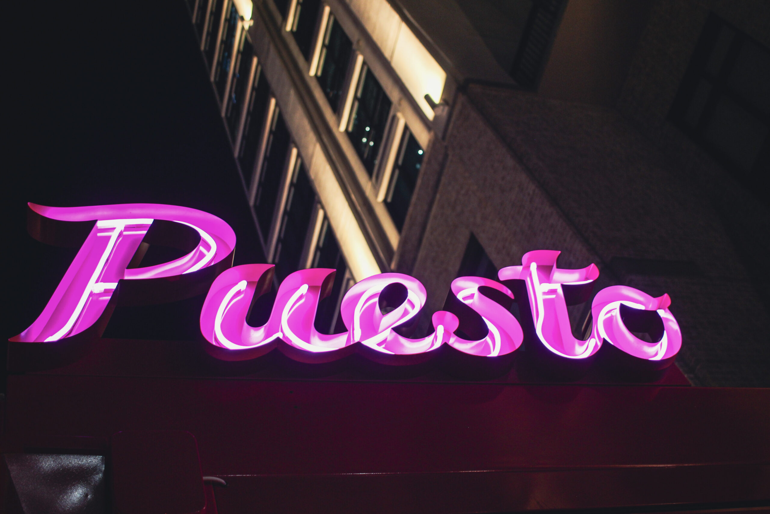  Puesto restaurant sign illuminated at night, viewed from the outdoor patio in Nashville Yards, Nashville, TN.