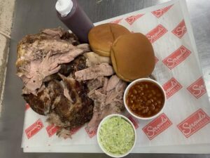 Smoked barbecue pork served with baked beans, coleslaw, buns, and barbecue sauce from Stroud’s Barbeque in Franklin, Tennessee.