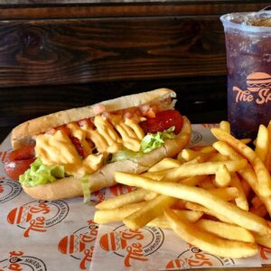 Hot dog topped with lettuce, tomato, and sauce served with french fries at The Spot Burgers & Beers in Spring Hill, Tennessee.